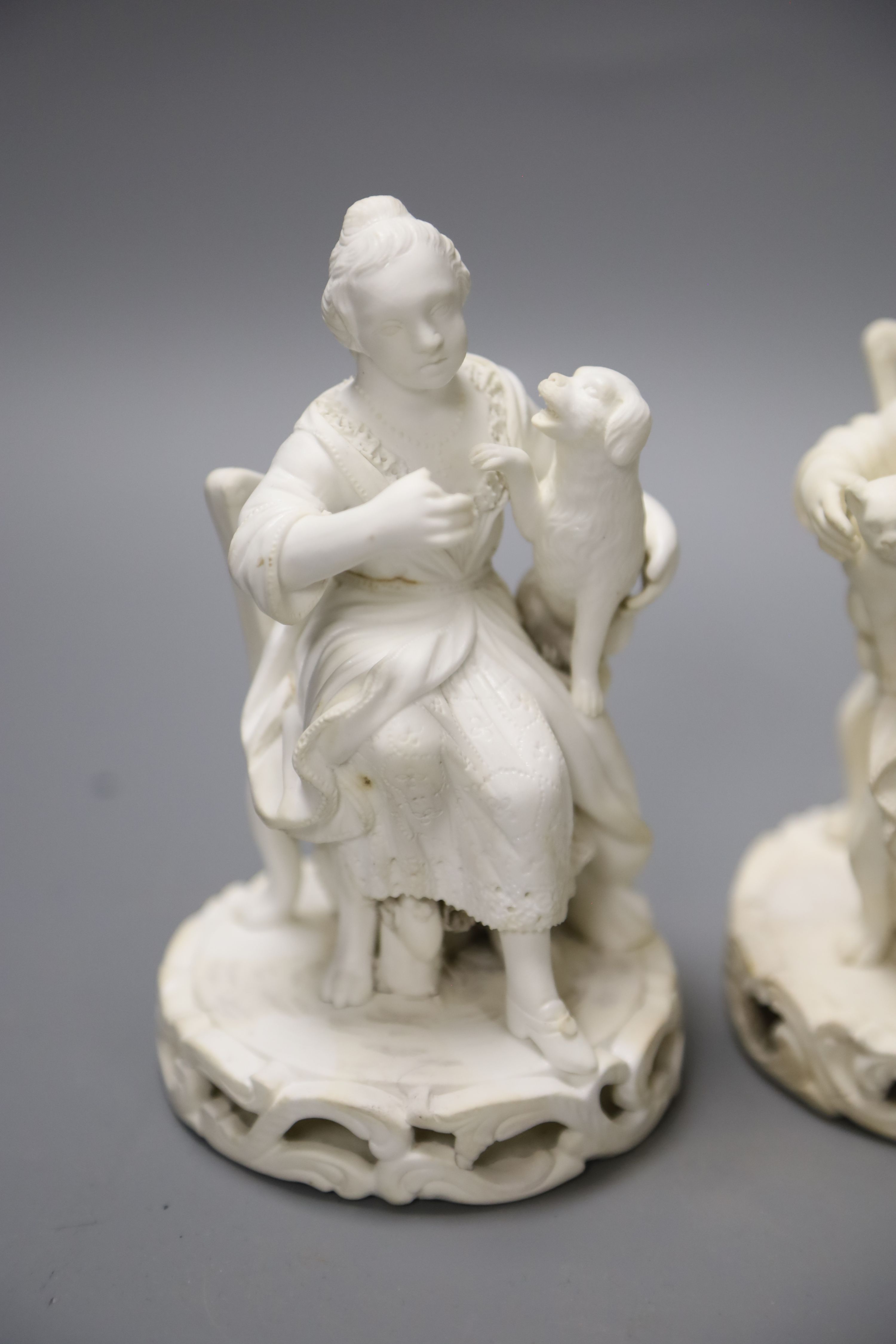 An early 19th century pair of Derby biscuit figures of a boy with a cat and a girl with a dog and a Minton figure of a Chelsea pensione